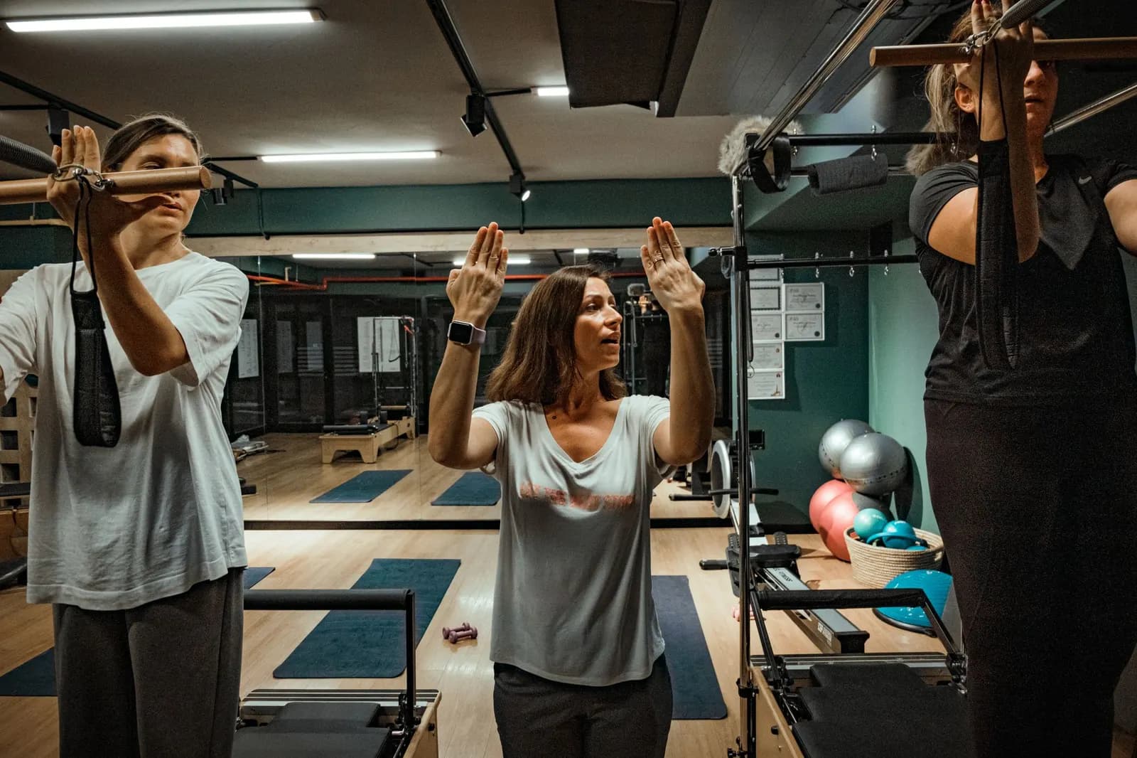 Γυμνάστρια καθοδηγεί δύο ασκούμενες σε studio pilates